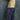 A young child standing in profile against a mottled blue-gray backdrop, wearing a yellow and cream striped long-sleeve top, navy pants with small white motifs and a paisley side panel, and purple sneakers.