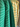 A close-up of striped collared shirts hanging on a rack, featuring a green shirt with thin white stripes, a green shirt with darker green stripes, and a yellow shirt with green stripes.